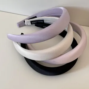Vista detallada de diademas de satén acolchadas en tonos crema con etiquetas handmade.