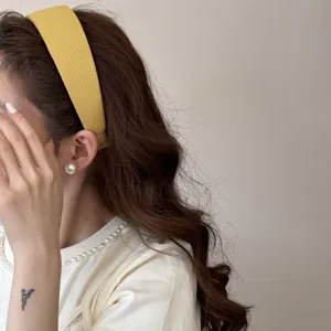 Side profile detail view of a yellow wide padded headband on a model with wavy hair.
