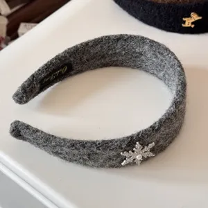 Close-up of a fuzzy gray headband featuring a delicate silver rhinestone snowflake accent.