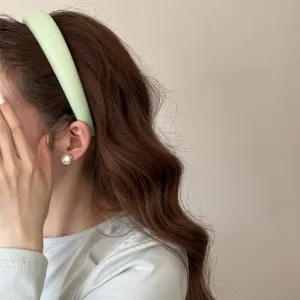 Gros plan sur un bandeau en éponge vert clair porté pour un look capillaire estival