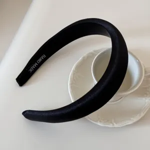 Vista detallada de una elegante diadema negra acolchada presentada sobre porcelana blanca