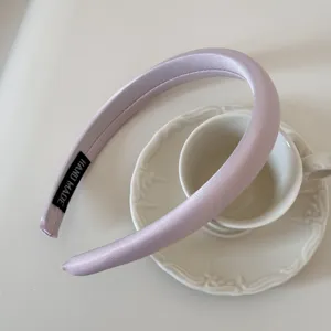 Detalle de una diadema de satén acolchada en color lavanda sobre un platillo
