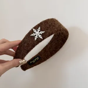 Close-up detail of a brown fuzzy winter headband featuring a rhinestone snowflake charm