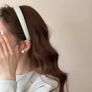 Vue détaillée d'un serre-tête en éponge vert menthe et d'une boucle d'oreille en perle.
