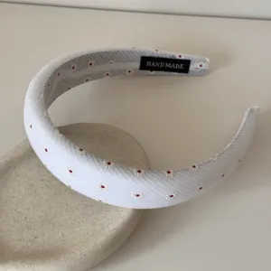 Dettaglio di un cerchietto in tessuto floreale con margherite e etichetta fatta a mano.