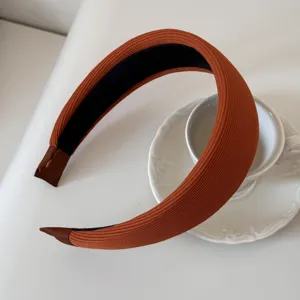 Detail view of high-quality orange ribbed fabric padded headband on white ceramic saucer