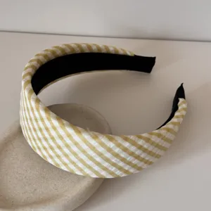 Détail d'un serre-tête à carreaux vichy jaune avec un design rembourré et élégant pour femmes.
