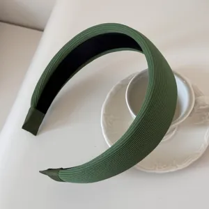 Detail view of a stylish wide green padded headband with soft ribbed fabric finish.