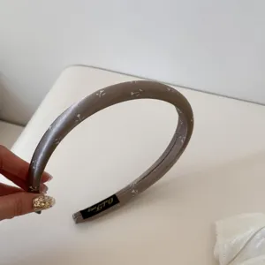 Détail d'un élégant serre-tête rembourré de couleur taupe à petits motifs floraux.