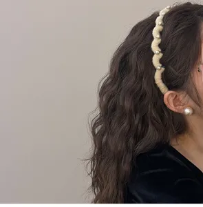 Side view of cream wave knitted headband with pearls on wavy brown hair