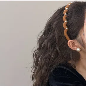 Close-up of brown wavy wool headband with elegant white pearl accents on long wavy hair.