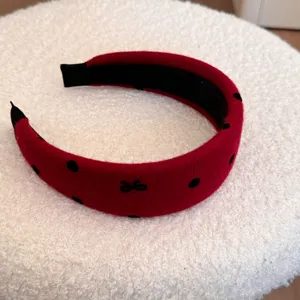 Détail d'un serre-tête en peluche rouge doux avec des pois noirs et un petit nœud