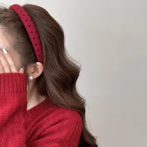 Close-up detail of a red wide-brimmed headband with black polka dots on an Asian model