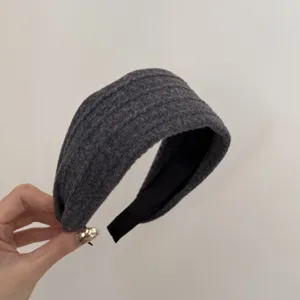Gros plan d'un serre-tête gris tricoté à motifs tressés au design vintage élégant