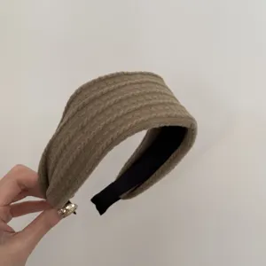 Gros plan détaillé d'un serre-tête en maille marron avec un motif de torsades doux