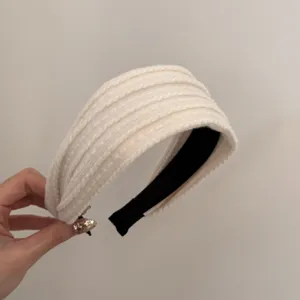 Détail d'un serre-tête en tricot blanc crème avec texture torsadée au style rétro chic