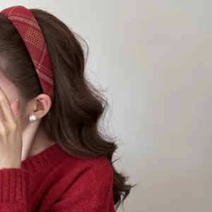 Détail d'un serre-tête d'hiver à carreaux rouges sur un mannequin, look coiffure haute.