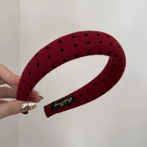 Detail view of red polka dot padded headband with soft fabric and interior label.