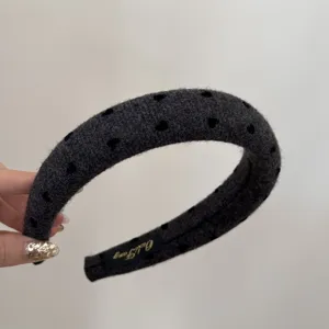 Detailed view of dark grey wide headband with black heart patterns and soft woolen texture