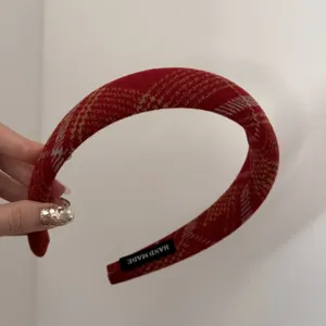 Vue détaillée du serre-tête en tissu à carreaux rouge et jaune avec étiquette fait main.