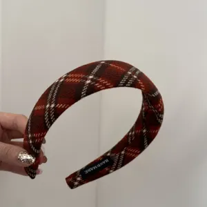 Détail d'un serre-tête rembourré à carreaux rouge et marron avec étiquette fait main.