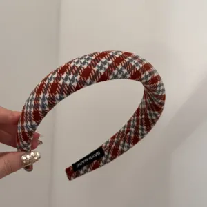 Gros plan d'un serre-tête à carreaux rouge et blanc avec une étiquette faite main.