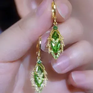 Vue détaillée d'élégantes boucles d'oreilles dorées avec des pierres vertes taille marquise.