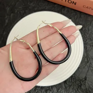 Close-up of elegant gold and black enamel oval hoop earrings for a luxury fashion look