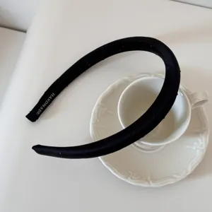 Vue détaillée d'un élégant serre-tête noir à pois avec un label fait main sur porcelaine blanche