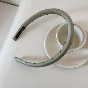Vue rapprochée d'un serre-tête vert sauge à pois avec une étiquette faite à la main.