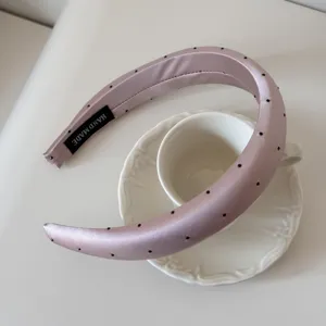 Détail du serre-tête en satin rose à pois avec étiquette 'HAND MADE' dedans