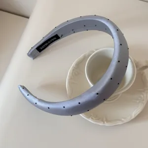 Détail en gros plan d'un serre-tête en satin bleu clair à pois noirs et fait à la main
