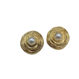 Close-up of elegant vintage gold spiral round stud earrings with central pearl detail