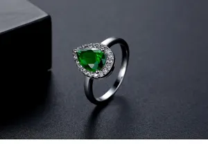 Detailweergave van de peervormige smaragdgroene ring met schitterende zirkonia-halo