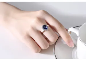 Close-up van een peervormige blauwe zirkonia ring aan een vinger met witte kop