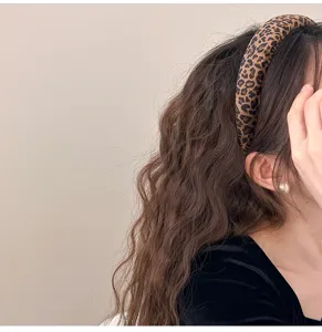 Gros plan d'un serre-tête en velours à motif léopard porté sur des cheveux bruns ondulés.
