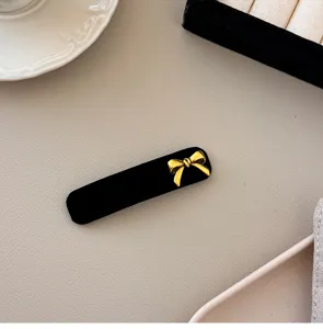 Close-up of an elegant black velvet hair clip with a vintage golden bow detail for women