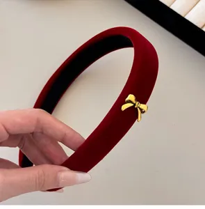 Close-up view of a luxury red velvet padded headband with a decorative gold bow charm