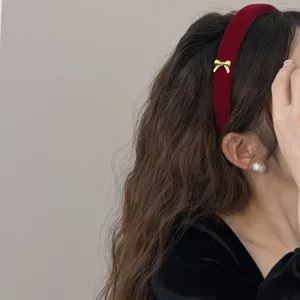 Elegant burgundy velvet headband featuring a delicate gold bow for a stylish winter look.
