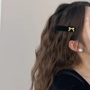 Elegant black velvet side hair clip with a small golden bow detail for women's styling