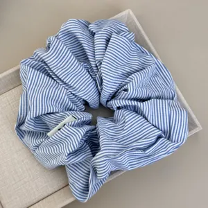 Close-up detail of a blue and white striped oversized fabric scrunchie in a tray