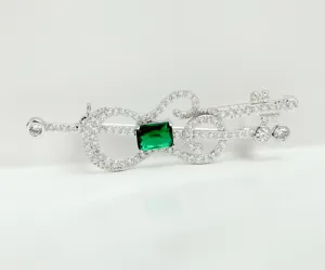 Elegant close-up of a retro guitar brooch with 3A cubic zirconia and emerald green stone.