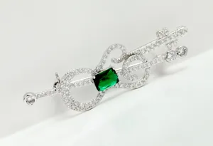 Detailed view of vintage guitar brooch with sparkling green and white zirconia.