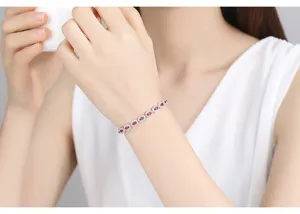 Primer plano de una pulsera de plata con circonitas AAA ovaladas rojas y blancas en la muñeca.
