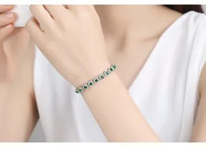 Elegante pulsera plateada con circonitas verdes en forma de corazón en la muñeca