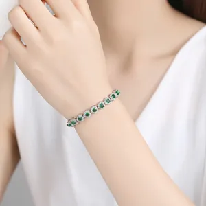 Elegante pulsera de corazón plateada con brillantes circonitas verdes en la muñeca