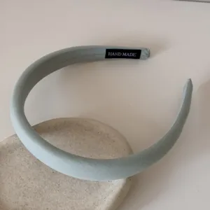 Gros plan d'un serre-tête en éponge vert clair avec étiquette Hand Made à l'intérieur