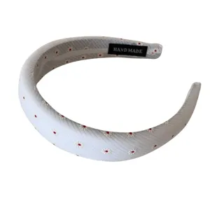 Elegante fascia larga in tessuto con piccole margherite ricamate su sfondo bianco