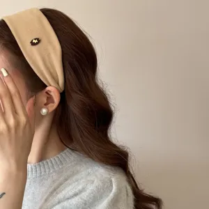 Vue détaillée d'un serre-tête chic en velours beige avec logo poney sur un mannequin.