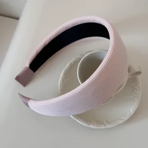 Detailed macro view of a light pink ribbed padded headband on a ceramic teacup.